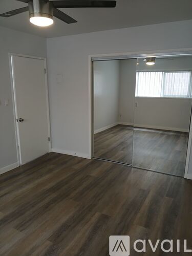 A room with a ceiling fan and wooden flooring.