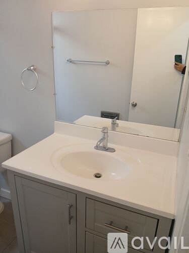 A bathroom with a white sink and grey cupboard.