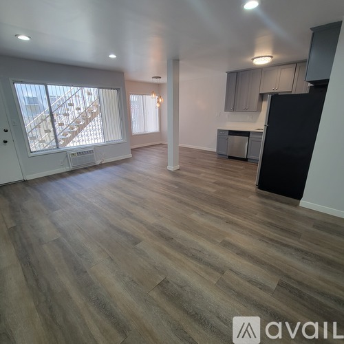 A spacious room with wooden flooring and a staircase leading to the upper level.