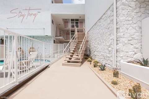 A white building with a sign that says "Stay Tuned" on the side.