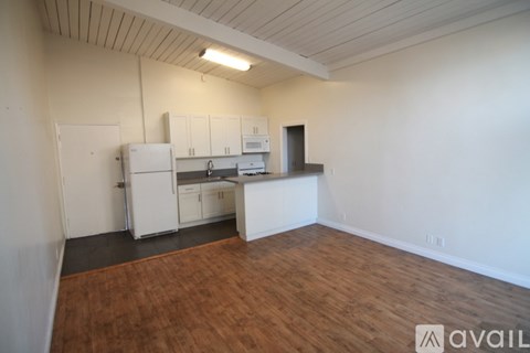 A kitchen area with white cabinets and a refrigerator.