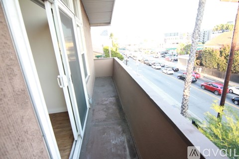 A balcony with a view of a street with cars and trees.