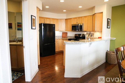 A kitchen with wooden cabinets and a black refrigerator.
