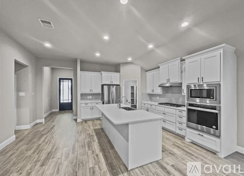A spacious kitchen with white cabinets and stainless steel appliances.