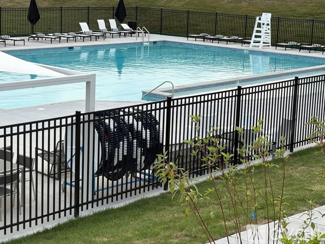 A pool with a black fence and a white ladder.