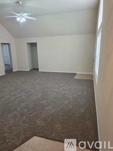 A spacious room with a carpeted floor and a ceiling fan.