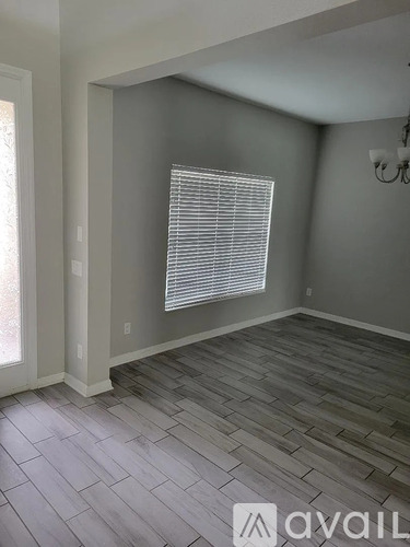 A room with wooden flooring and a window with blinds.
