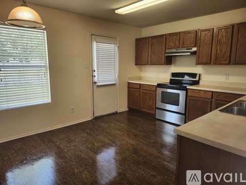 A kitchen with brown flooring and wooden cabinets.