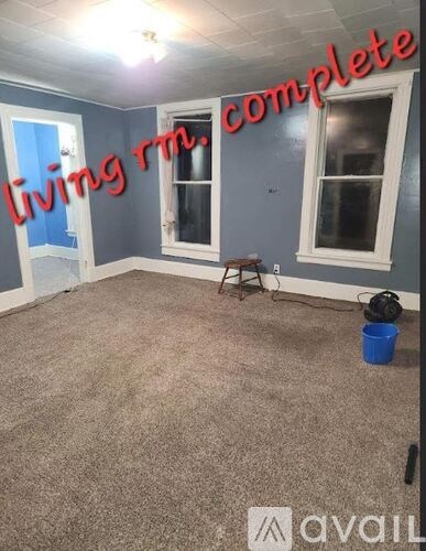 A room with a carpeted floor and a window is available for rent.