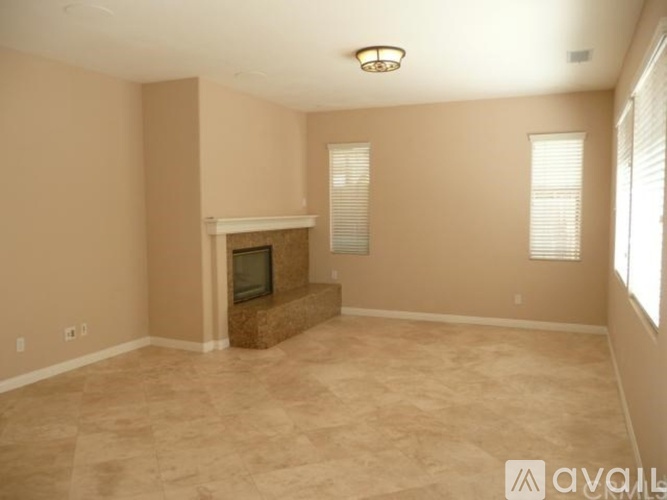 A living room with a fireplace and a window with blinds.