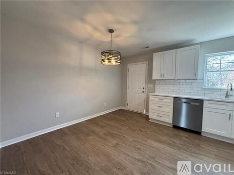 A kitchen with white cabinets and a wooden floor.