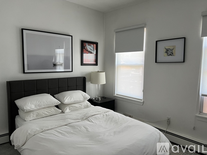 A bedroom with a large bed, a nightstand with a lamp, and three framed pictures on the wall.