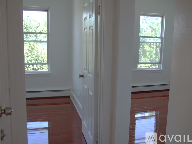 A room with a white door and a window with trees visible outside.
