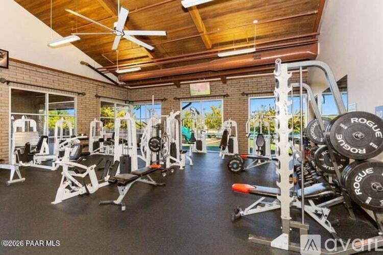 A well-equipped gym with a variety of exercise machines and a ceiling fan.