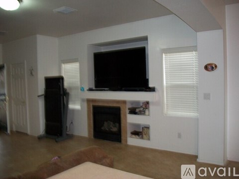 A living room with a fireplace and a television mounted above it.