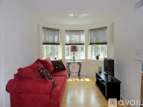 A red couch sits in a living room with a television and a small table.