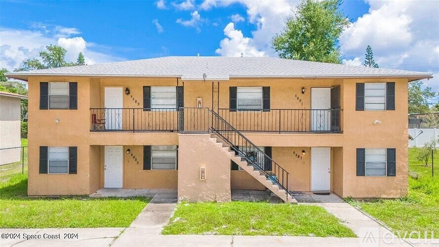 A two-story apartment building with a balcony on the second floor.