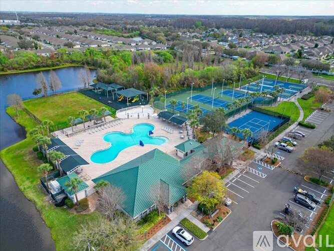An aerial view of a tennis court surrounded by a parking lot and a body of water.