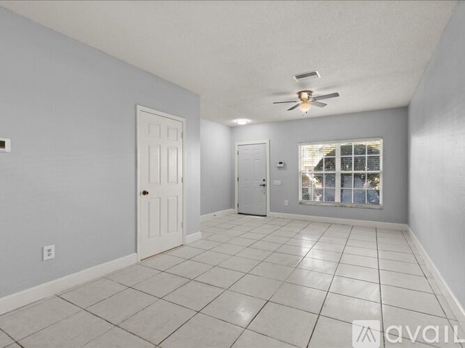 A spacious room with a ceiling fan and tiled flooring.