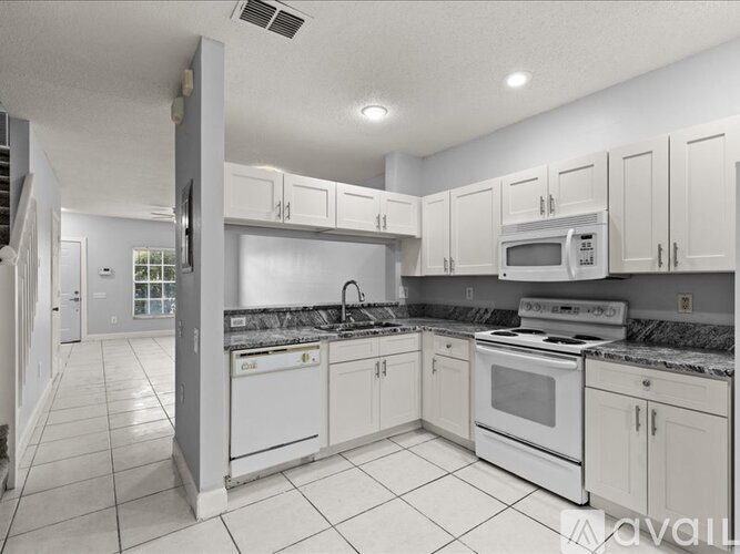A kitchen with white cabinets and appliances.