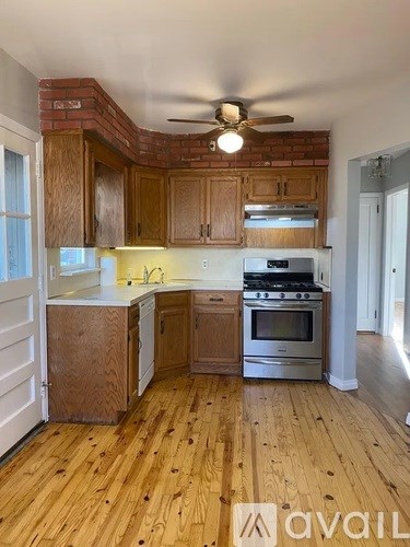 A kitchen with wooden cabinets and a brick wall.