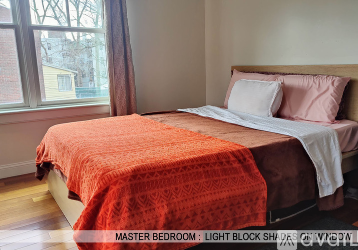 A bedroom with a bed covered in an orange blanket.