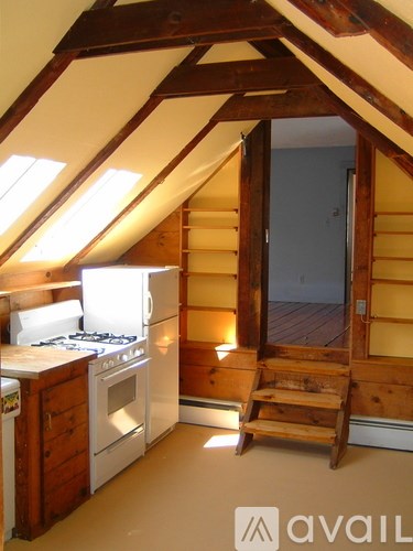 A small kitchen with a stove top oven and a wooden staircase.