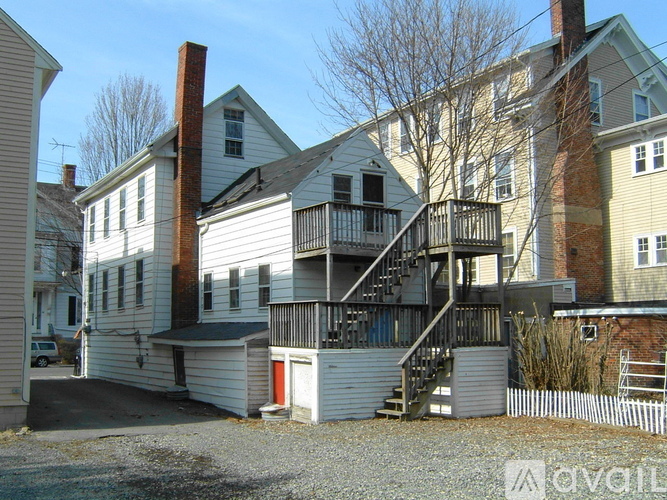 A house with a white exterior and a red door is surrounded by other houses.