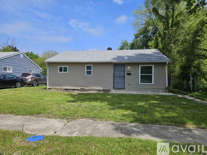 A small house with a grey roof and a sign that says "AVAIL" in front of it.