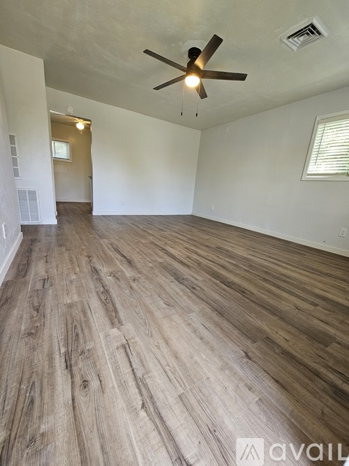 A room with wooden flooring and a ceiling fan.