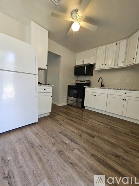 A kitchen with a white refrigerator and wooden floors.