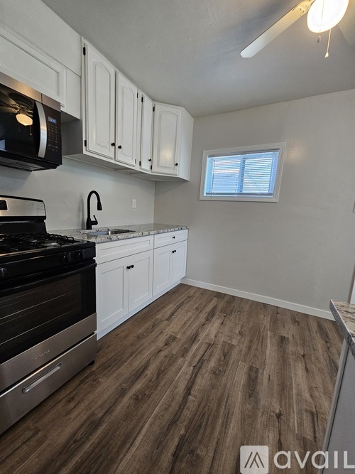 A kitchen with white cabinets and a black stove top oven.