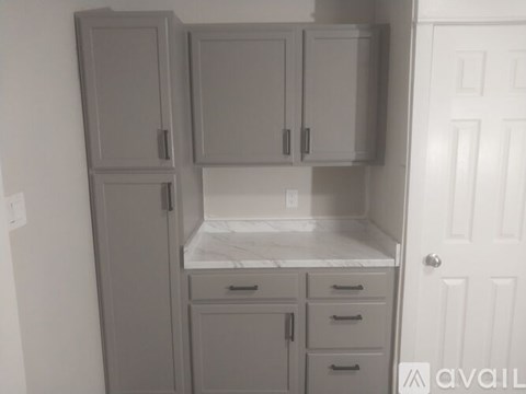 A kitchen with grey cabinets and a white door.