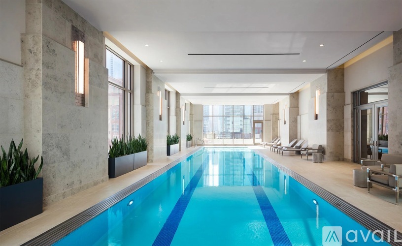 A large indoor swimming pool with lounge chairs and plants on the side.