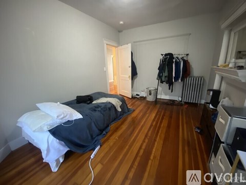 A bedroom with a bed, a closet, and a wooden floor.