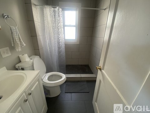 A white toilet with a white sink and a shower curtain in a bathroom.