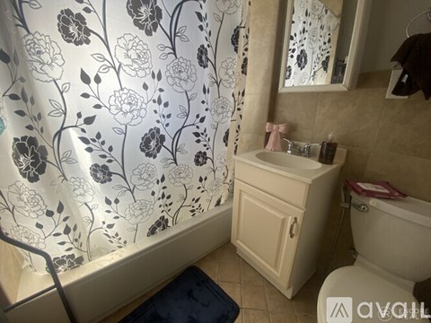 A bathroom with a floral shower curtain and a white sink.