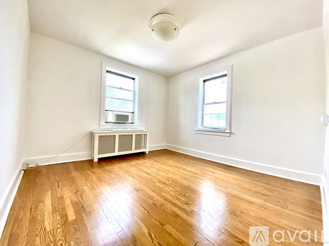 A room with wooden floors and two windows.