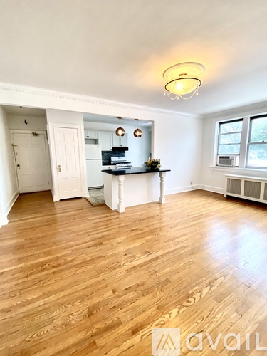A room with wooden floors and a white kitchen area.