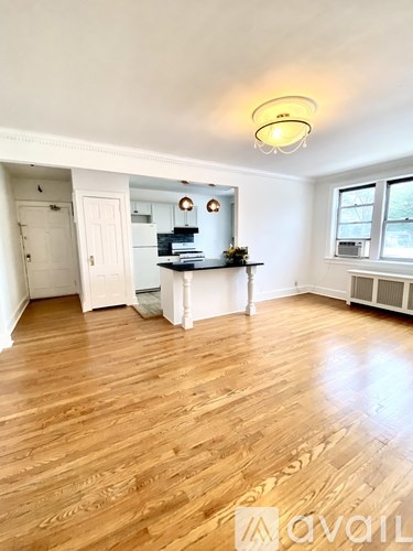 A room with wooden floors and a white kitchen area.
