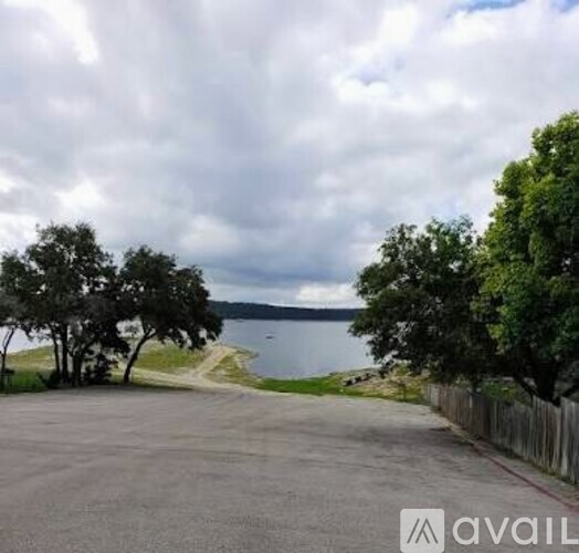 A parking lot with a lake and trees in the background.