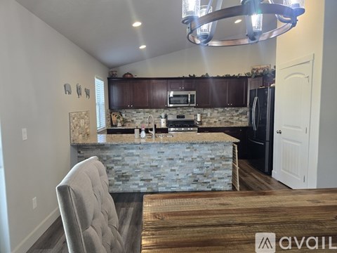 A kitchen with a stone counter top and a grey chair.