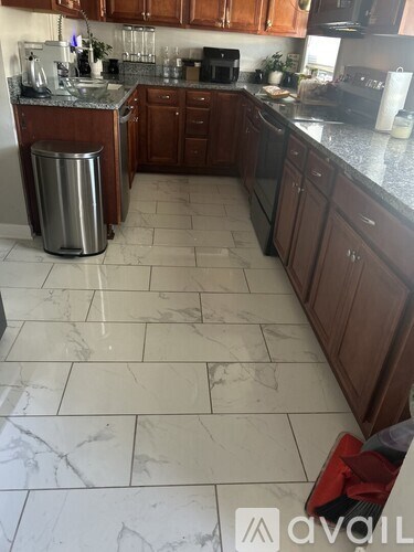 A kitchen with brown cabinets and a marble floor.