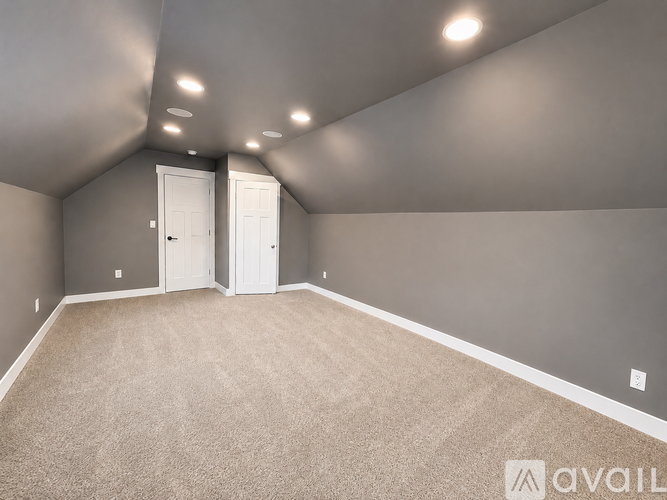A spacious room with carpeted floor and two white doors.