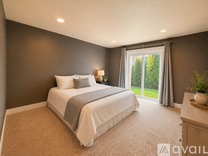 A bedroom with a large bed and a window overlooking a green area.
