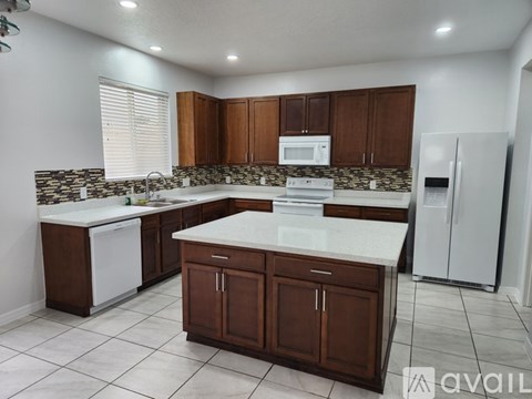 A kitchen with brown cabinets and white appliances.
