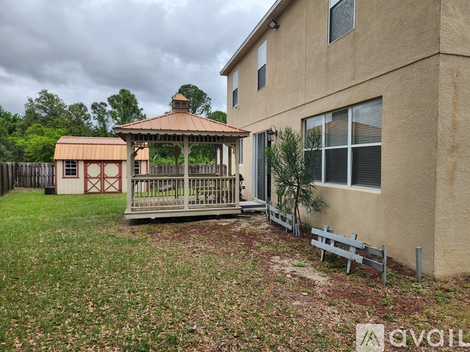 A gazebo is in the front yard of a beige house.