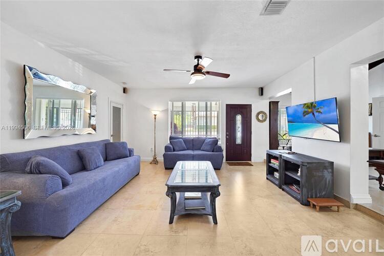 A living room with a blue couch and a ceiling fan.
