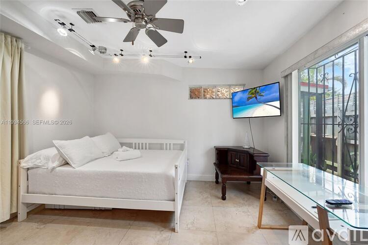 A bedroom with a bed, a television, and a glass table.