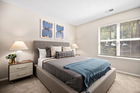 A bedroom with a bed, two lamps, and a window.
